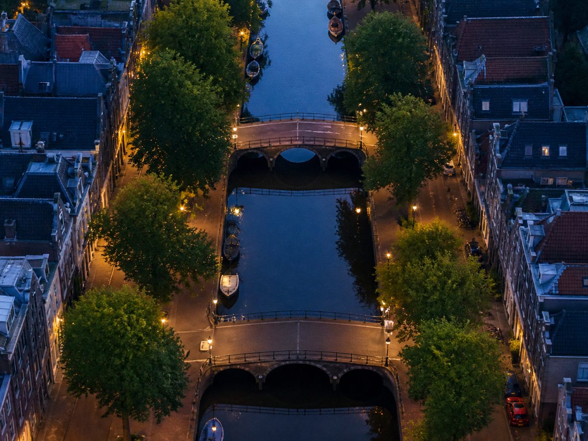 Kanaal met bruggen en bomenrijen in avondlicht, schuin van boven