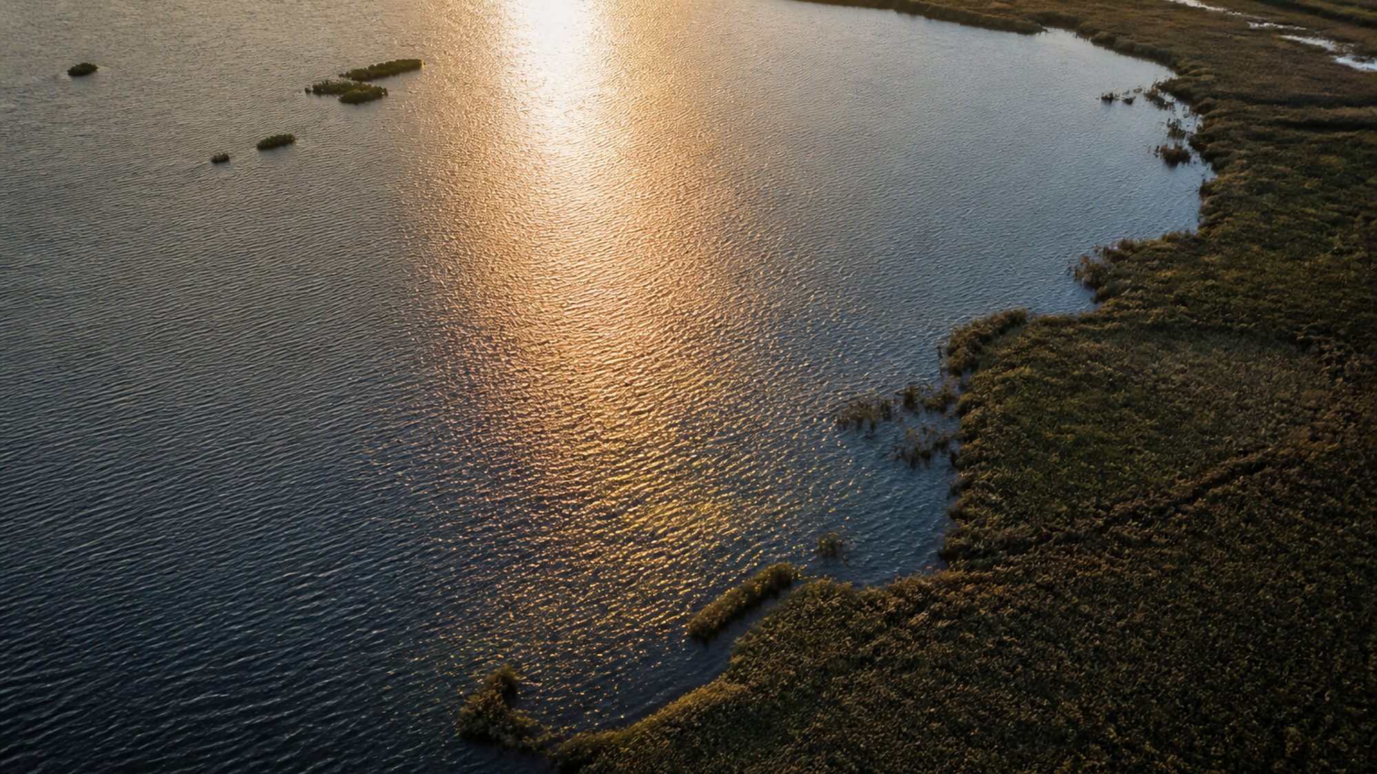 Binnenmeer bij zonsondergang met een glinsterend zonnepad over het water