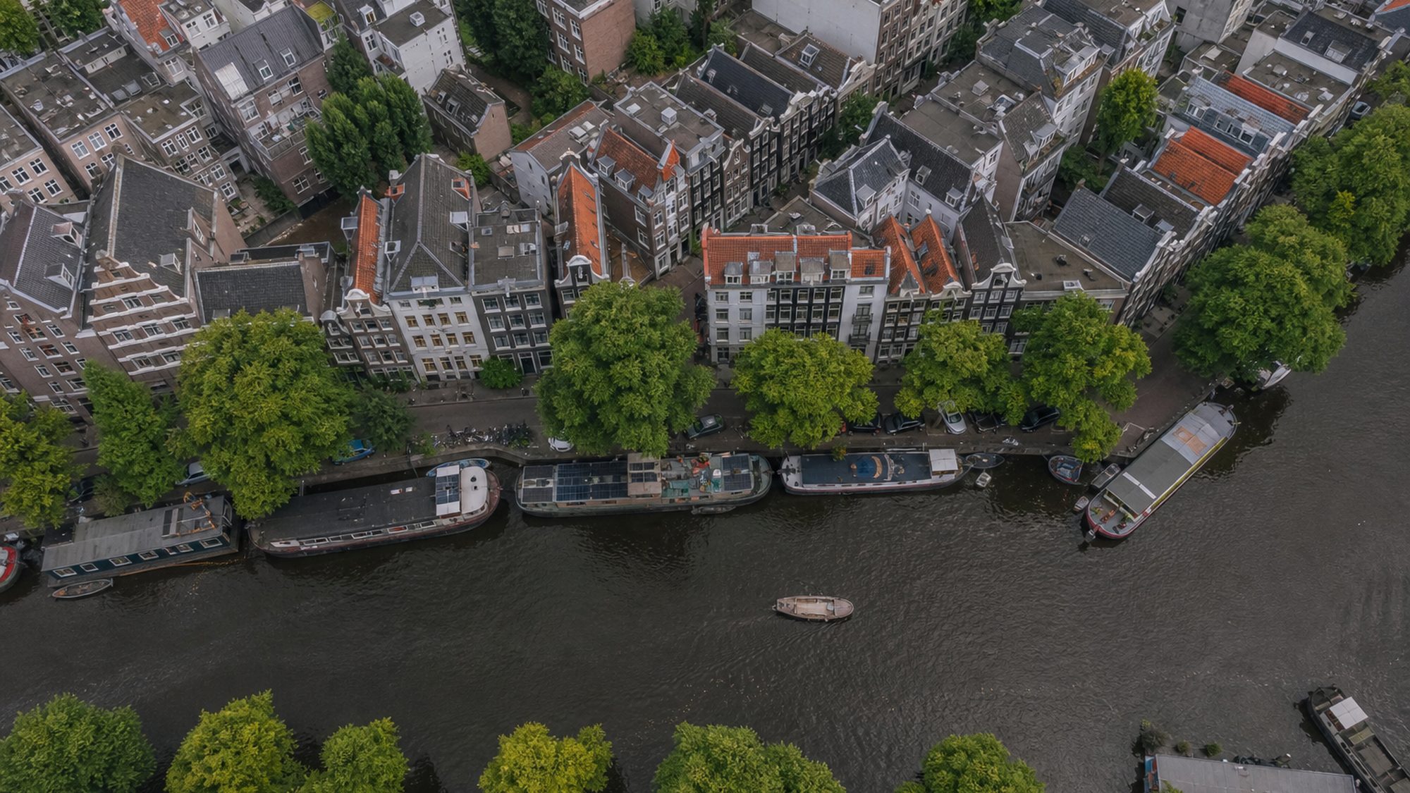Stadsgracht van boven met woonboten langs de kade en bomenrijen