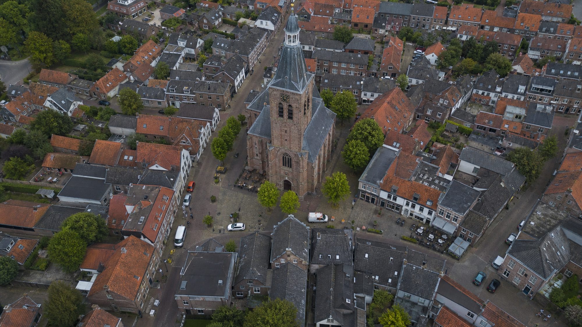 Dorpskern van bovenaf met een bakstenen kerktoren en rode pannendaken
