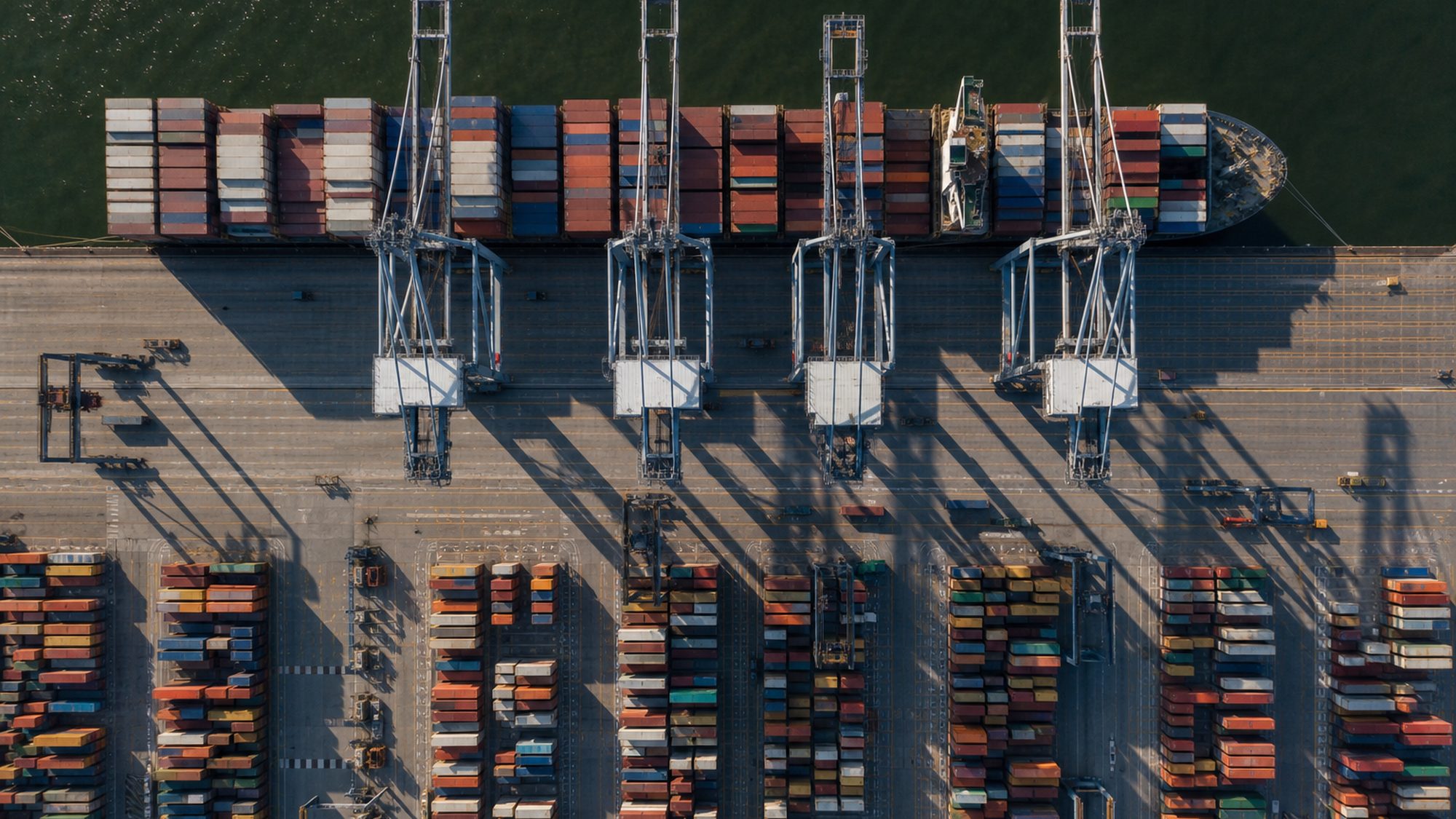 Containerterminal van bovenaf met gestapelde containers en portaalkranen